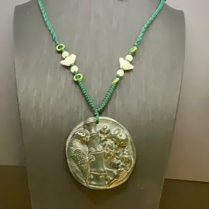Dark green jade pendant with adjustable silk cord.